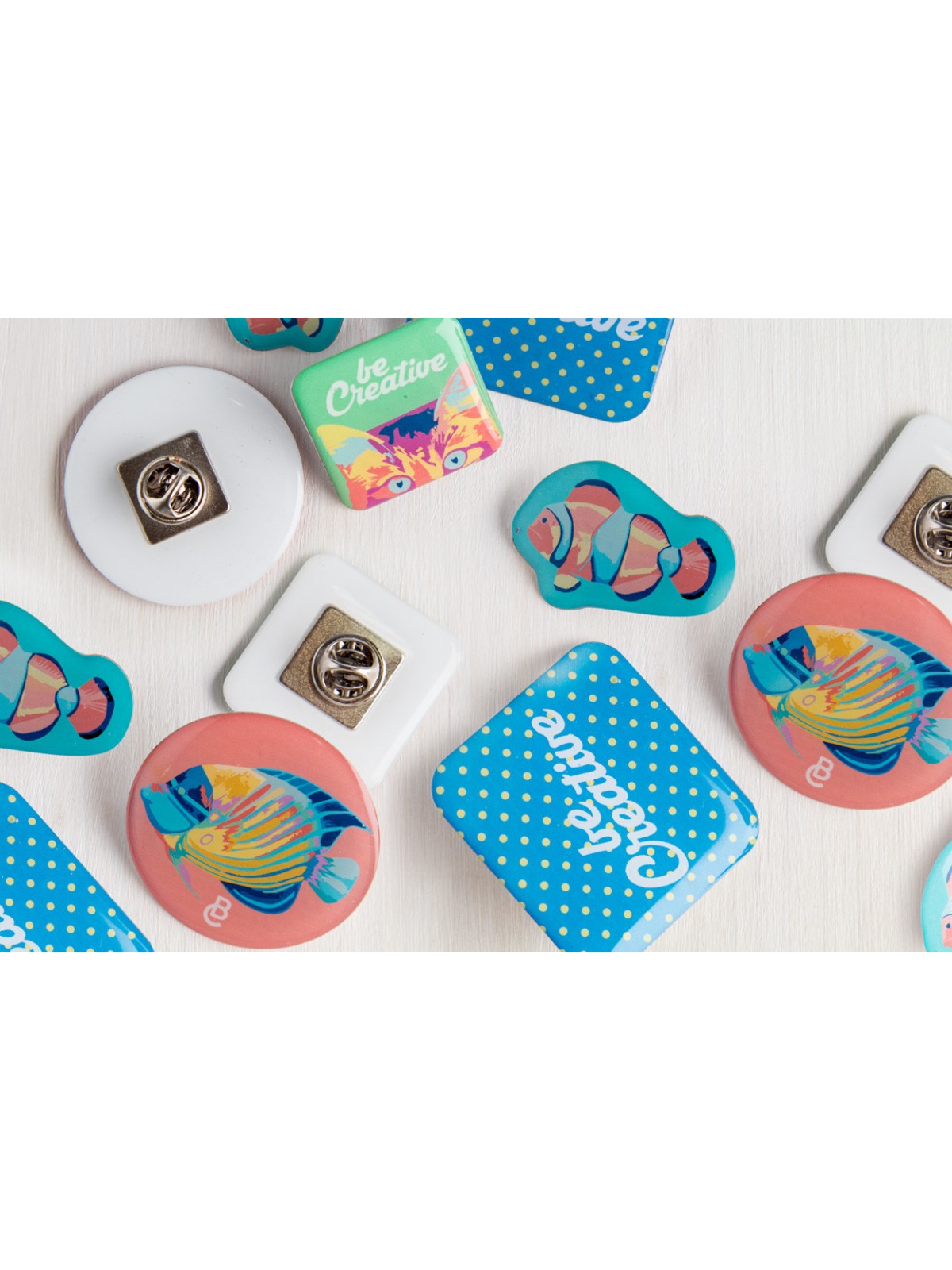 Plusieurs maxi badges carrés et ronds en résine personnalisés avec des logos et visuels de poisson